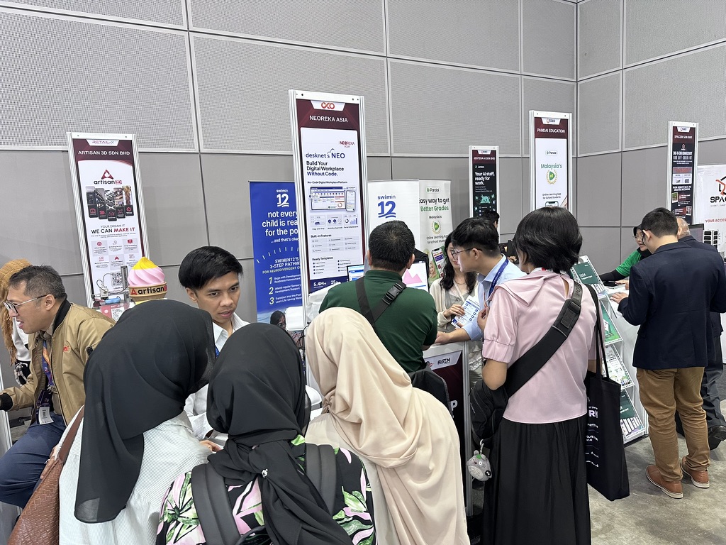 Visitors gathered at the NEOREKA ASIA booth beside the desknet's NEO 'Build Your Digital Workplace Without Code' standee at AiSEM@Selangor 2026, KLCC